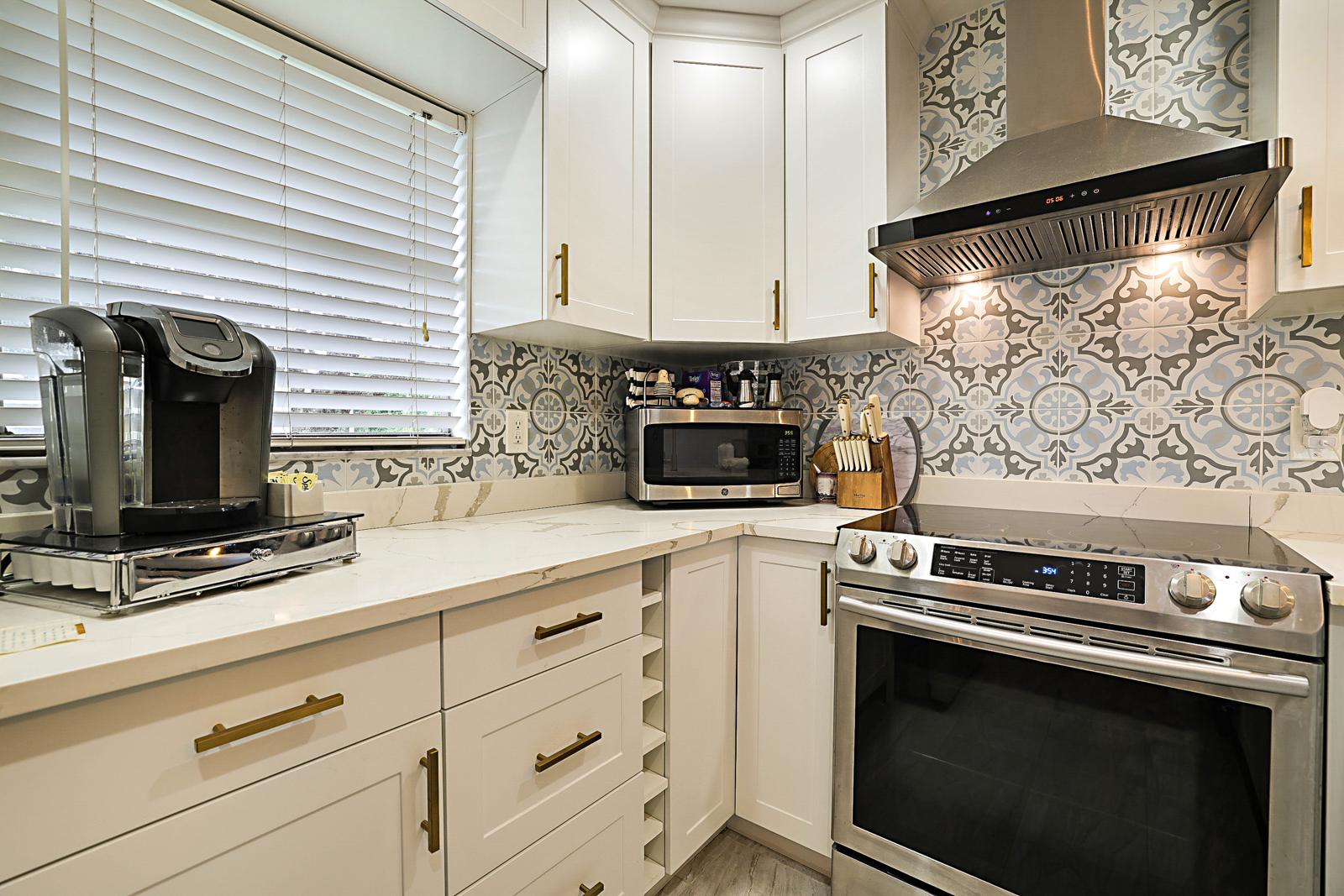 136 Tuscany B, Delray Beach, FL 33446 - kitchen with patterned tile backsplash and range hood